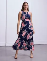 Vestido largo de seda fría con estampado floral en tonos rosados y blancos sobre fondo azul marino. Presenta cuello redondo con abertura en forma de ojal y aplique metálico.