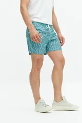 Short de baño turquesa con estampado abstracto en blanco, cintura elástica con cordón ajustable, dos bolsillos laterales y uno trasero.