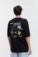 Remera color café de corte oversize con cuello redondo y mangas cortas. Estampado en la espalda con la frase "Stay Original Forever" y varios diseños gráficos.
