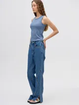 Pantalón de jean azul de tiro alto y corte oxford con apliques metálicos en bolsillos y laterales.