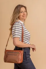 Bandolera marrón de cuero sintético con detalles en nobuck, cierre principal y cierres adicionales en la parte trasera y delantera.