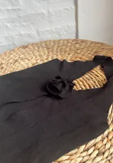 Top negro con escote halter y abertura frontal con detalle de rosa.