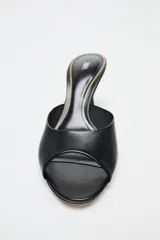 Zapato tipo mule de cuero negro con punta redonda y tacón fino.