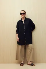 Vestido camisero negro de silueta amplia, con cuello camisero, botonadura frontal completa y mangas largas.