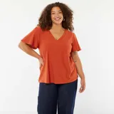 Camiseta color ladrillo de punto calado con escote en V y mangas cortas tipo murciélago.