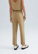 Pantalón carrot color beige, de tiro alto, con cintura elástica y bolsillos laterales.