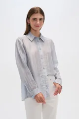 Camisa celeste de lyocell con textura arrugada, corte holgado, cuello clásico y cierre frontal con botones.