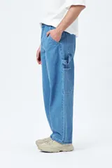 Pantalón jean negro de corte amplio y estilo carpenter, con tiro medio, bolsillos utilitarios y presillas laterales.