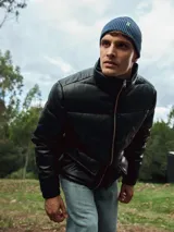 Campera puffer negra de poliéster con cierre de cremallera, cuello alto, puños elásticos y bolsillos laterales.