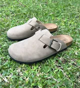 Sandalias beige con hebilla ajustable, suela de corcho y base negra.