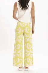 Pantalón palazzo de tejido de punto color amarillo con estampado de hojas blancas.