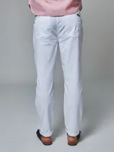 Pantalón color beige de corte regular fit, confeccionado en lino. Cuenta con dos bolsillos frontales y dos bolsillos posteriores, bajo con botamanga y presilla, aplique de badana.