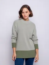 Polerón de manga larga con cuello alto, diseñado en dos colores y con cierres en los costados.