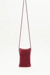 Bolso pequeño tipo cartera porta celular, confeccionado en terciopelo color borgoña con diseño bordado de tulipanes dorados. Tiene acceso superior con cierre y tirante en hilo metalizado, más cordón largo que permite colgarlo al cuerpo.