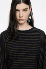 Camiseta de tejido de punto con rayas horizontales en tonos azul marino y verde oliva. Presenta escote redondo y mangas largas estilo murciélago o raglán.