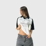 Polo oversize blanco y negro con cuello clásico, mangas cortas y estampado con el logo de la marca en el frente.
