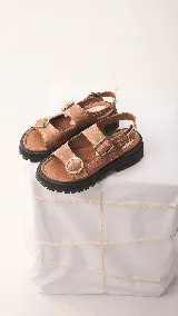 Sandalias marrones con suela track y tiras anchas con hebillas metálicas.