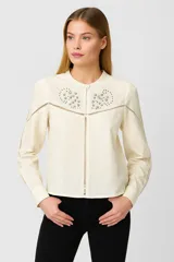 Blusa color blanco con cuello mao, manga larga con puños abotonados, cierre frontal con botones ocultos y detalle de bordado con strass en el canesú.
