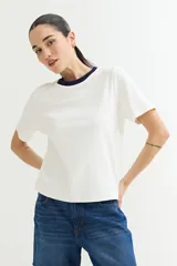 Remera blanca de algodón con cuello redondo y mangas cortas. El cuello es de color azul marino en contraste.