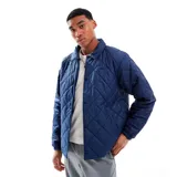 Campera Nike acolchada color azul marino, con cuello camisero, cierre con botones a presión y logo bordado en el pecho. Tiene bolsillos laterales y puños elásticos. Corte regular.