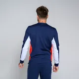 Buzo deportivo Umbro del Club Nacional de Football, modelo Premier, color azul marino con detalles en blanco en los puños y paneles laterales en rojo. Presenta el escudo del club en el pecho.