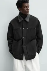Parka negra de algodón con cuello solapa de cuero sintético, corte recto, acolchada, con bolsillos de parche y cierre frontal con botones.