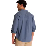 Camisa de manga larga color celeste, con cuello clásico, cierre frontal con botones y bolsillo en el pecho izquierdo con logo de la marca. Las mangas pueden enrollarse y sujetarse con una tira. Corte recto y dobladillo camisero.