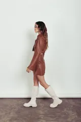 Campera corta de cuero ovino color caramelo, de mangas largas acampanadas y cuello camisero.