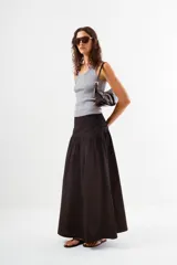 Falda larga de color negro, con cintura lisa y un amplio volado fruncido que comienza a la altura de la cadera, aportando volumen y movimiento.