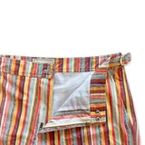 Short de baño con estampado de rayas horizontales y motivos geométricos en tonos naranja, marrón y blanco. Cuenta con pretina elástica y cordón ajustable.