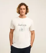 Remera color crudo de corte clásico, con cuello redondo y mangas cortas. Estampado frontal con la frase "Yacht Club" y un dibujo de un velero.