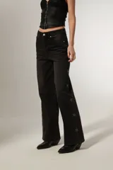 Pantalón jean negro de corte ancho y tiro alto, con bolsillos y apliques de strass en forma de estrella en los laterales.