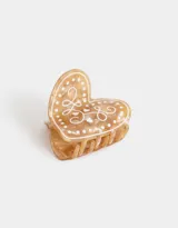 Broche para el pelo en forma de corazón color crema con diseño de lunares y arabescos en blanco.