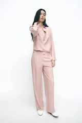 Camisa color rosa de manga larga, con cuello solapa, trabillas en los hombros, bolsillo delantero y cierre frontal con botones.