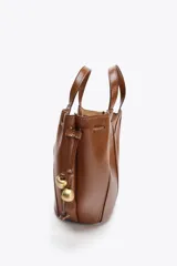 Bolso de mano color marrón con detalle de pespuntes en el cuerpo y tiradores laterales con abalorios en efecto metalizado. Tiene doble asa de mano y correa extraíble para usar como bandolera. Incluye cartera interior con cierre de cremallera y cierre imantado.