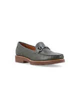 Mocasín de cuero negro con detalle de hebilla metálica plateada.
