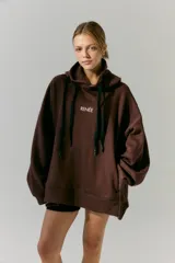 Buzo marrón de frisa con capucha y bolsillos delanteros. Corte oversize, recortes laterales y doble cordón con puntera de goma. Estampa en frente y espalda realizada en serigrafía con diseño de llavero con dijes.