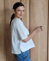 Remera negra con cuello redondo y mangas cortas, con detalle de pespuntes blancos en cuello, mangas, bolsillos frontales y ruedo.