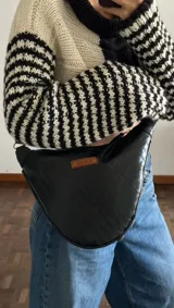 Bandolera negra de cuero con textura croco, correa ajustable y logo de la marca en etiqueta de cuero.