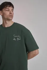 Remera verde oscuro de corte oversize con estampado pequeño en el frente.