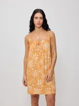 Vestido corto negro con estampado de palmeras, soles y estrellas en color crema. Diseño suelto con breteles finos y escote recto con lazo ajustable.