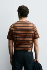 Camiseta marrón con rayas horizontales color naranja, de corte relaxed fit, cuello redondo a contraste y manga corta.