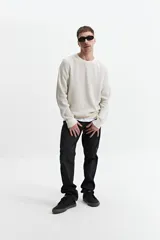 Buzo de punto color crudo, de corte oversize, con cuello redondo y puños.