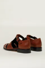 Sandalia roja de cuero vacuno con diseño de tiras entrecruzadas y hebilla lateral. Tiene suela de cuero artesanal y taco bajo.