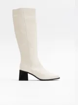 Bota alta color hueso, con caña recta, punta cuadrada y taco bloque negro.