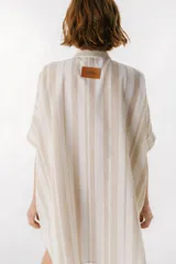 Camisa oversize con cuello mao, manga corta con terminación en puño, botones de metal a la vista y tajos laterales.