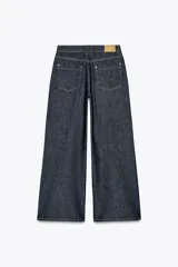 Pantalón de jean azul oscuro, de tiro alto y corte wide leg. Tiene cinco bolsillos, cierre frontal con cremallera y botón.