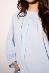 Camisa celeste super holgada con hombro caído y manga ancha. Tiene un volado en el cuello y efecto arrugado en la espalda.