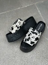 Sandalias tipo sueco con plataforma de goma negra y tira ancha de cuero con estampado animal print de vaca.