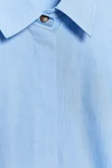 Camisa celeste de algodón con corte crop, cuello solapa, mangas largas con puños y cierre frontal con botones ocultos.